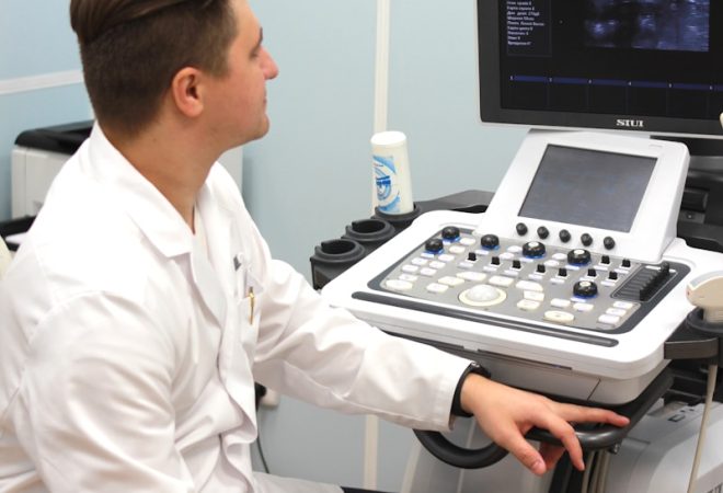 a man in a white lab coat sitting in front of a computer