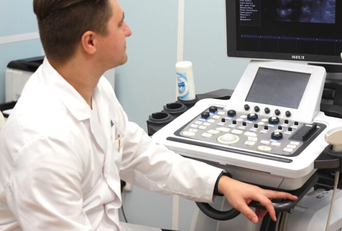 a man in a white lab coat sitting in front of a computer