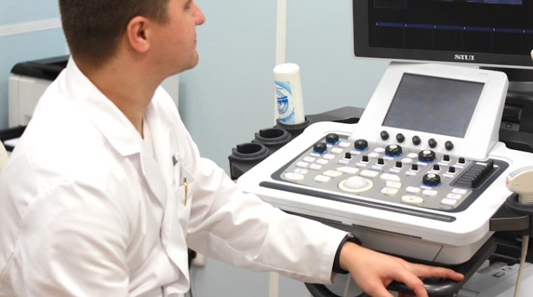a man in a white lab coat sitting in front of a computer