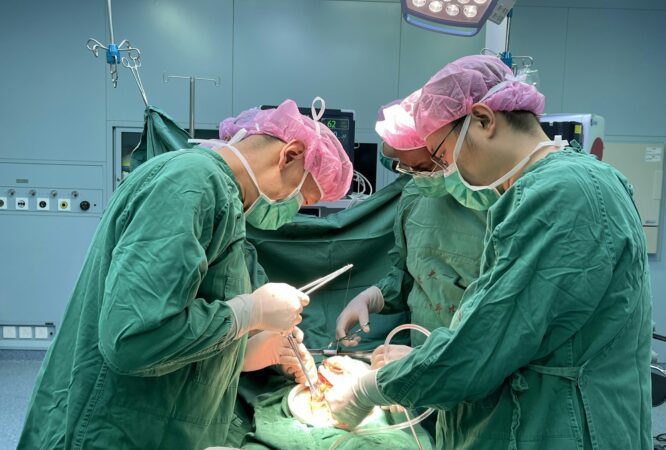 Surgeons performing a medical operation in a hospital operating room.