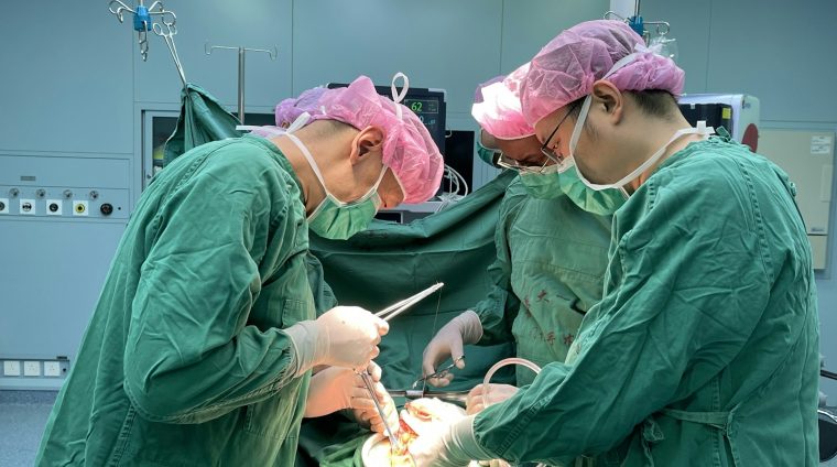 Surgeons performing a medical operation in a hospital operating room.